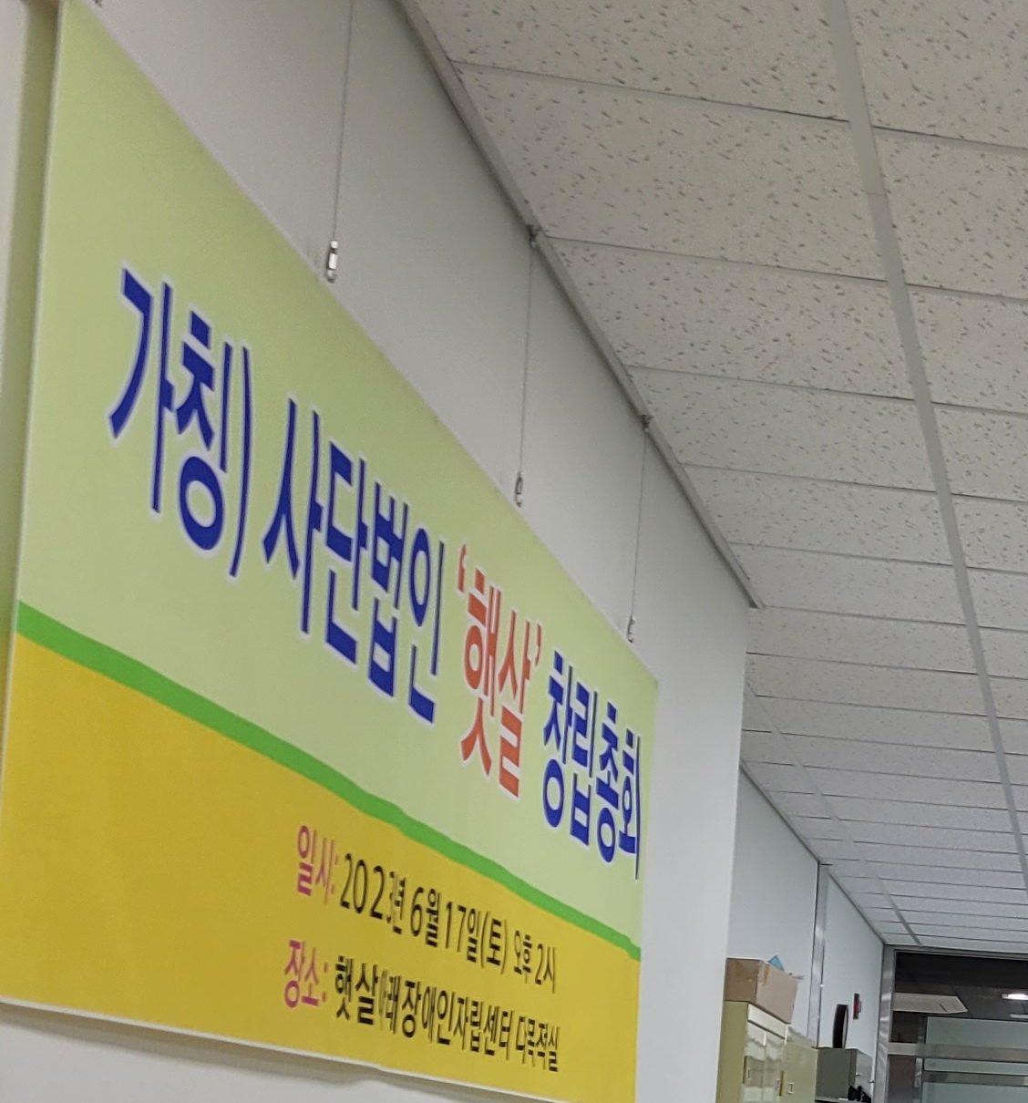 복도 벽에 걸린 창립총회 현수막. 「(가칭) 사단법인 '햇살' 창립총회」와 일시 2023년 6월 17일 토요일 오후 2시가 적혀 있다.